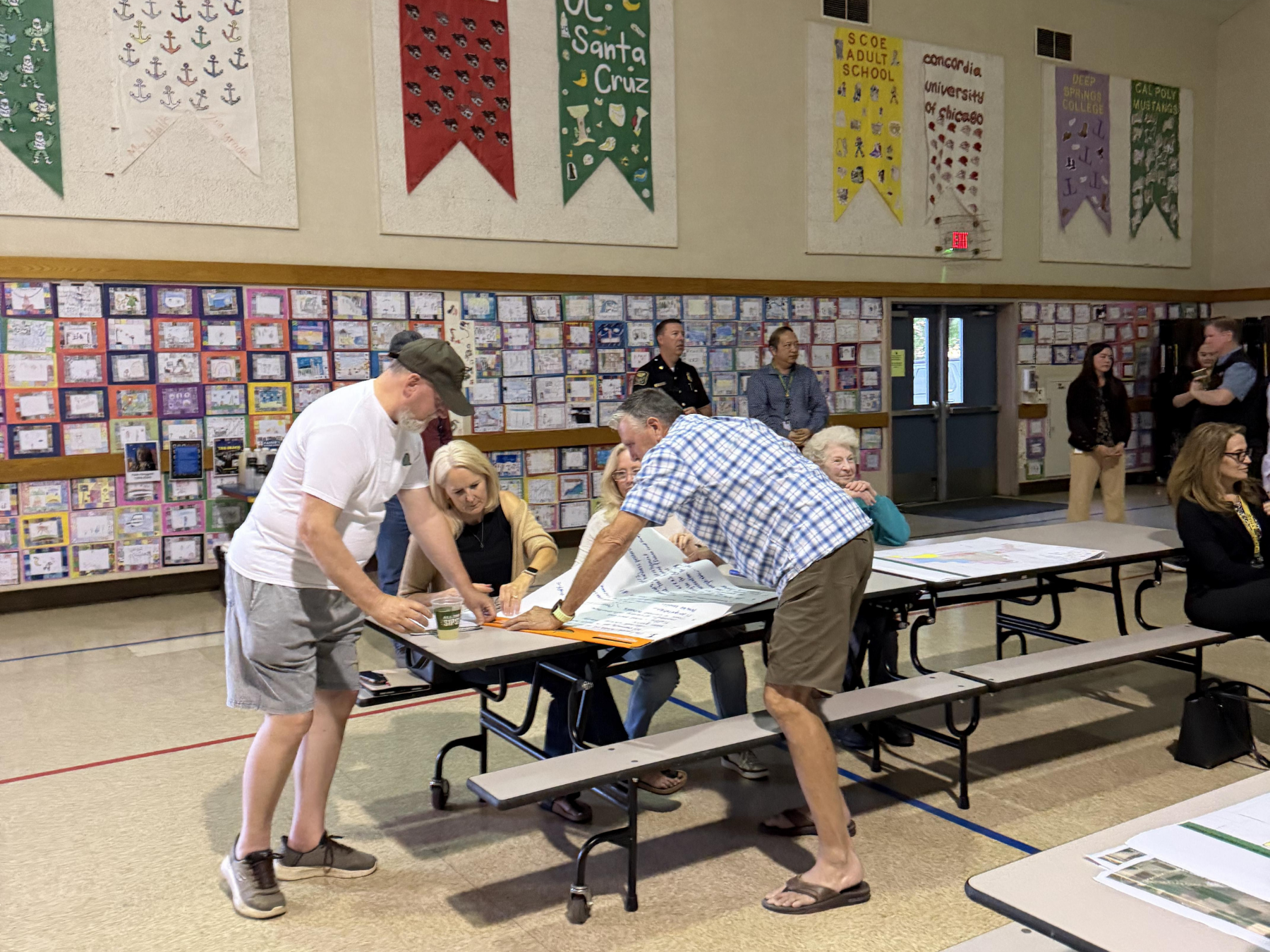 People gather around a table in a community center, actively discussing and flip charts.