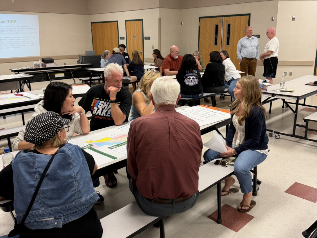 Attendees sit around a table discussing maps and notes in small groups at the community workshop.